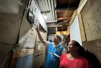 Umi (kanan), salah satu warga Jalan Rela, Kelurahan Menteng Atas, Kecamatan Setia Budi, Jakarta Selatan tampak bahagia dengan kehadiran listrik yang disambung oleh petugas PLN.